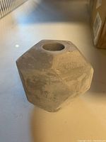 Close-up side view of a cement candle stick holder showing its faceted geometric shape and candle hole.