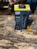 Philips Series 5000 hair clipper box, CW Beggs and Sons moisturizing shave cream, Proraso mustache wax, and plastic spinning tie/belt holder on countertop.