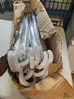 Box of 24 transparent dog umbrellas with white handles, partially packed, showing the curved handles and packaging condition.