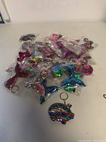 Lot of 30 sequin keychains shown packaged on a table, featuring multiple shapes and colors including a starfish shaped keychain and others