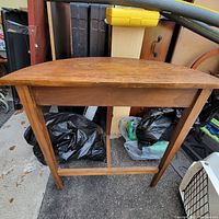 Front view of the wooden half table showing tapered rectangular legs with horizontal lower support, and rounded half moon top surface.