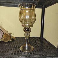 Amber-tinted glass candle holder with flared top and rounded stem on a flat base
