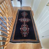 Full view of rectangular Persian rug laid on hardwood floor showing blue background with floral medallions and borders.