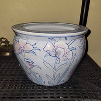 Front view of blue and white ceramic planter showing floral design and flared rim with geometric border.