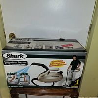 Front of the Shark Professional Portable Hard Surface Steam Cleaner box showing product image, usage examples, and branding.