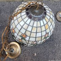 Full view of Tiffany style stained glass hanging lamp showing floral elements, the bronze chain, and top fixture.