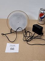 Front view of the circular electronic lamp with mesh and power cord attached. Power adapter is also shown with the lamp.