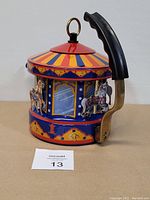 Front and side view of enamel tea kettle with carousel horses and colorful roof design