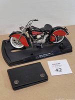 Side view of the Indian Chief 1948 motorcycle replica on black display base with black leather wallet in front.