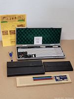 Overview photo showing the entire lot with drafting set, cases, pencils, rulers, and instruction sheet.