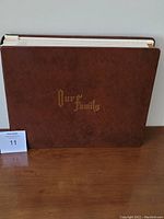 Closed view of brown simulated leather photo album with gold embossed text 'Our Family' on the front cover, showing size and condition.
