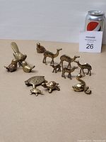 Photo showing all brass animal figurines arranged on beige surface with soda can for scale