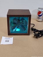Front view of the vintage stroboscopic light with woodgrain casing and blue-tinted glass lens, showing reflective interior parts.
