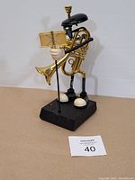 Front and side view of the vintage dancing trumpet player toy, showing music stand, trumpet, hat and base.