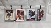 Four hockey cards clipped on display rack, multiple players shown