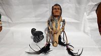 Photo of the figurine, coyote skull display, and small carved figure showing front view with details.