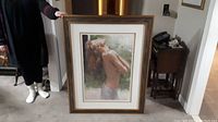 Full view of the large framed print held upright by a person, showing the front image clearly.