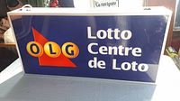 Front view of the Lotto Centre light-up sign showing blue background with OLG logo and Lotto Centre de Loto text. The sign is rectangular and shows some scratches and wear.