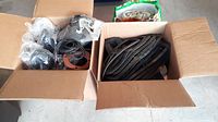 Two open cardboard boxes and one bag containing rubber and neoprene gaskets and O-ring materials.