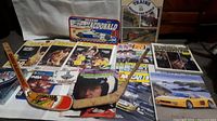 Photo showing multiple vintage sports magazines, a small signed Blackhawks hockey mini stick, and several sports memorabilia items on a surface.