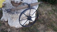 Vintage wooden yoke resting on a large tree stump, showing wood texture and iron ring supports with visible wear and damage