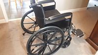 Side view of the black Tracer EX2 manual wheelchair showing large rear wheels, padded armrests, and footrests.