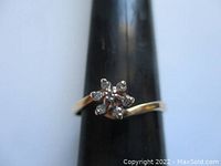 Front view showing the flower-shaped diamond cluster mounted on a black ring mandrel.