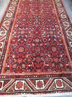 Full-length view of red and ivory patterned runner rug on wooden floor