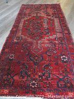 Full view of the Persian Hamdan wool rug laid out on a floor showing its rich wine and red colors with intricate traditional geometric and floral designs.