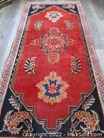 Full view of the rectangular rug showing the central medallion, floral motifs on red background and contrasting borders