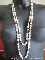 Full length view of the doubled pearl necklace on display form showing alternating white and dark pearls.