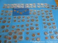 Top-down view of multiple sealed uncirculated Canadian coin sets arranged on blue background.