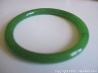 Lighter green jade bangle shown alone on white background.