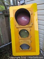 Front view of full-size yellow traffic signal, showing red, amber, and unlit green lenses