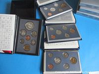 Four sets of Canadian coins in display boxes with blue inserts, including multiple denominations and designs in uncirculated condition.