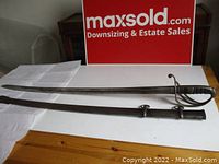 Full view of saber and scabbard laid flat on tabletop