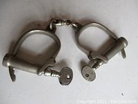 Photo showing both handcuffs with keys inserted in locks, metal chain connecting cuffs visible