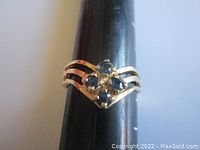 Front view on ring mandrel showing cluster of four blue sapphires and split shank band