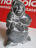 Front view of hand carved black stone Inuit hunter holding a seal with detailed facial carving.