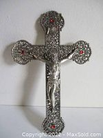 Front view of vintage solid silver metal cross with Jesus figure and red accent stones at each end.