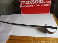 Full-length view of saber laid on table showing curved blade and guard