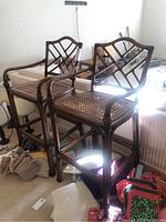 Two bamboo bar stools with cane woven seats and lattice backs placed side by side showing full view.