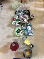 Overview of lot contents showing multiple glass bowls, vases, candles, candle melter, and decorative items.