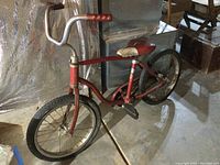 Full view of the red vintage Schwinn child's bicycle with visible rust and wear.