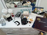 View of dresser top with vintage cameras, ginger jars, shell trinket box, opera glasses, clamp mount, and two yearbooks