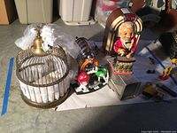 Image of various items including decorative birdcage, M&M figurines with diner straw holder, animated bartender toy, and faux jukebox radio on floor.