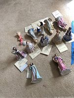 Overall group of 11 Lenox figurines arranged on floor with certificates of authenticity placed beside several of them.