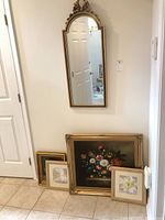 View of decorative wall mirror and four framed wall art pieces on floor