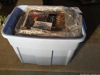 Light blue plastic bin filled with assorted vinyl records and a sealed plastic bag labeled 'Mostly Rock & Roll 50s'