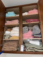 Full view of the wooden cabinet with four shelves holding assorted towels of various colors and sizes.